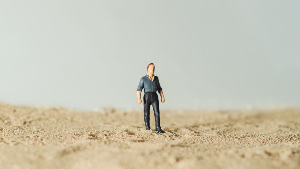 a toy man standing in the middle of a desert