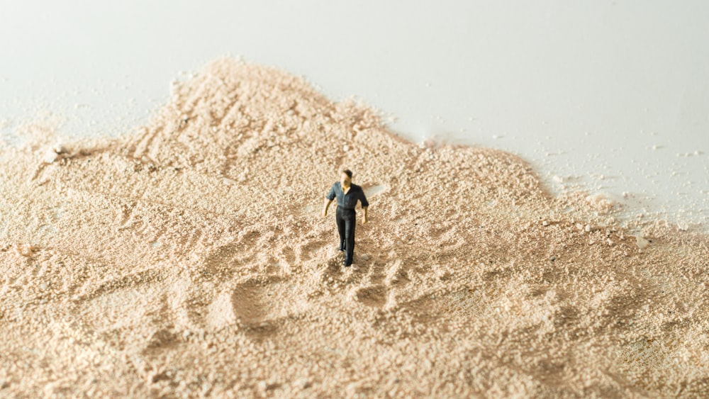 a miniature man standing in a pile of sand