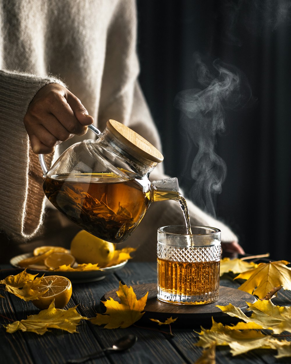 a person pouring tea into a glass pitcher