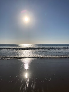 A warm, sunlit family beach scene with children building sandcastles under a blue sky.