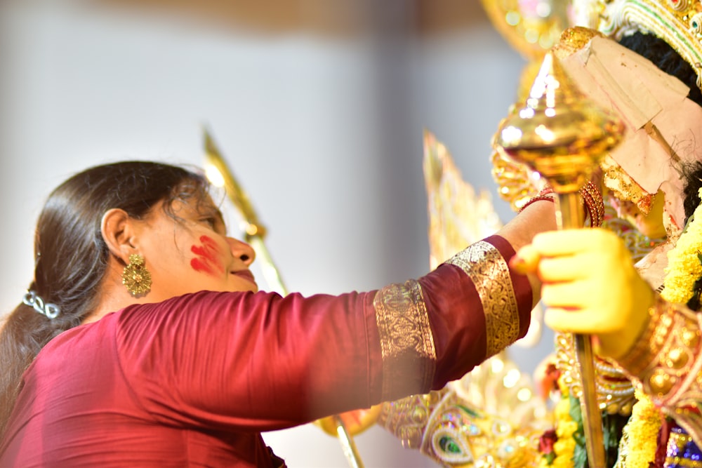 a woman in a red shirt is putting decorations on a tree