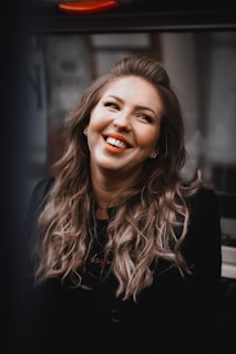 A joyful smile framed by voluminous, healthy hair cascading over shoulders.