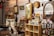 A variety of vintage items are displayed on shelves in a cluttered space, including framed pictures, signs, and glassware. There are decorative items such as old signs, a lamp, and a mirror with a wooden frame. Shelves are filled with assorted collectibles, including small jars, boxes, and figurines.