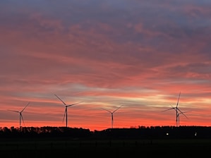A wind turbine farm set against a dramatic landscape at sunset.