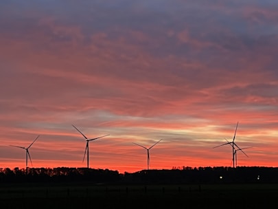 A wind turbine farm set against a dramatic landscape at sunset.