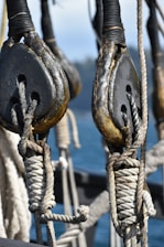 Close-up of a rope access technician inspecting a ship's hull in a port setting.