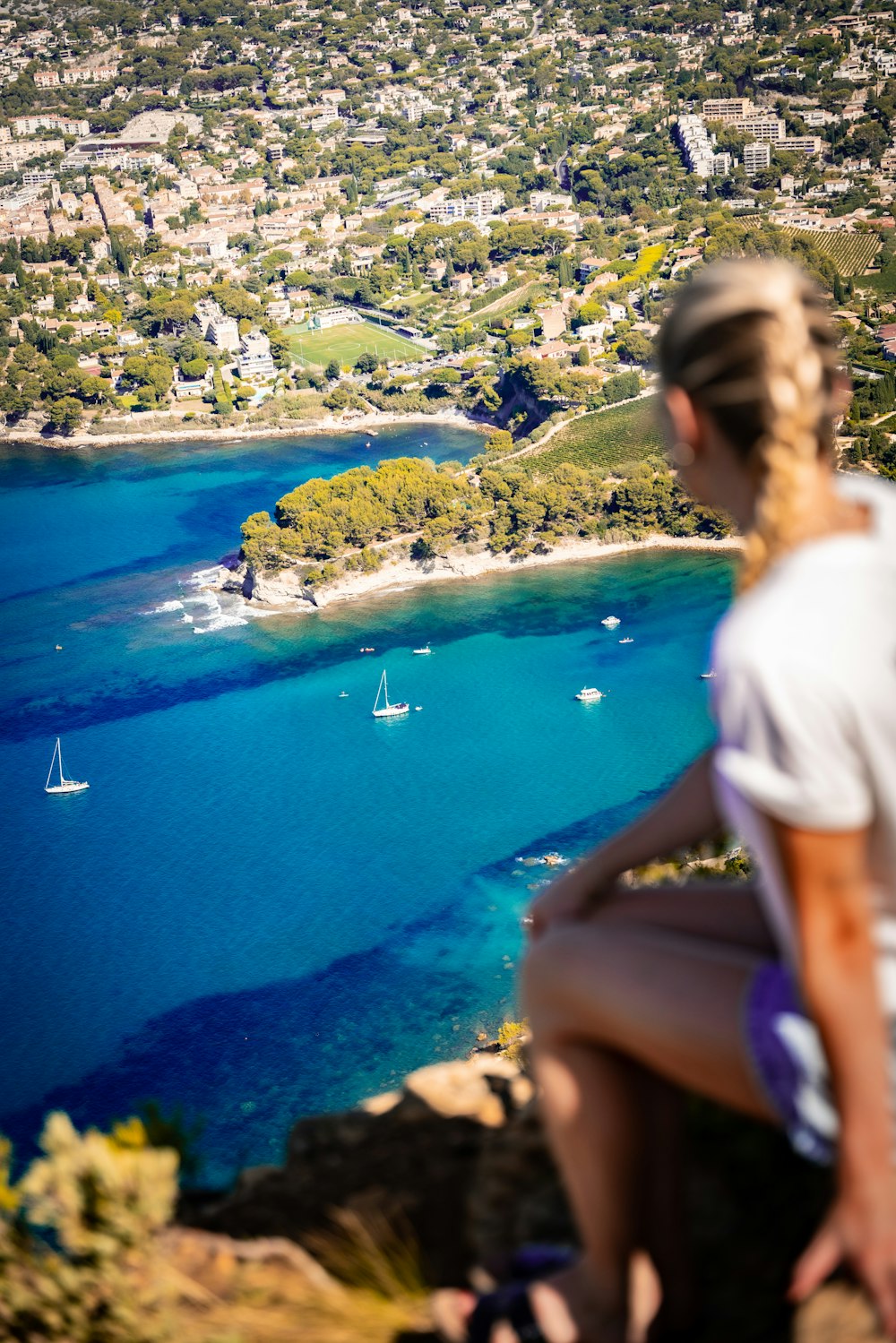 a woman sitting on top of a cliff overlooking a lake