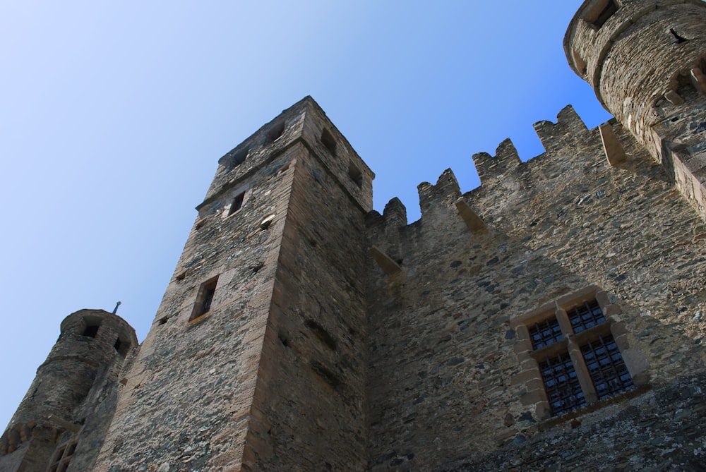 Un castillo de piedra con dos ventanas y un fondo de cielo