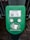 A green electronic device for ticket activation with instructions in Russian. It features a QR code, NFC symbol, and an illustration indicating where to place a card. The background consists of a pavement area partially visible.