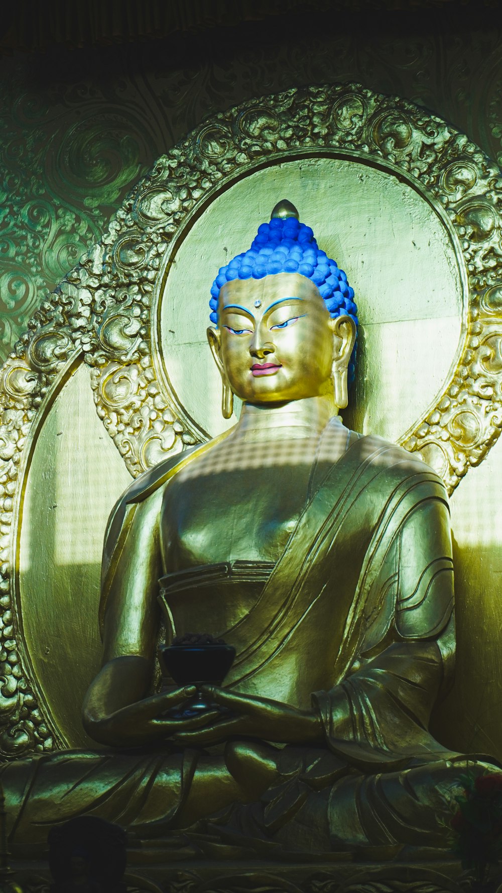 a golden buddha statue sitting in front of a wall