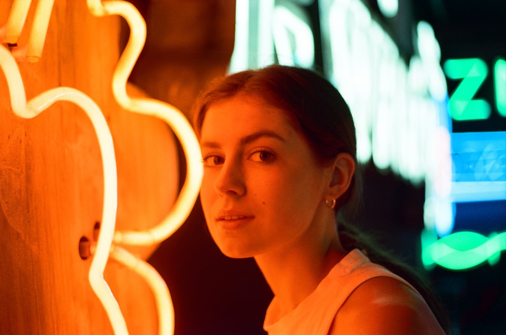 a woman standing in front of a neon sign