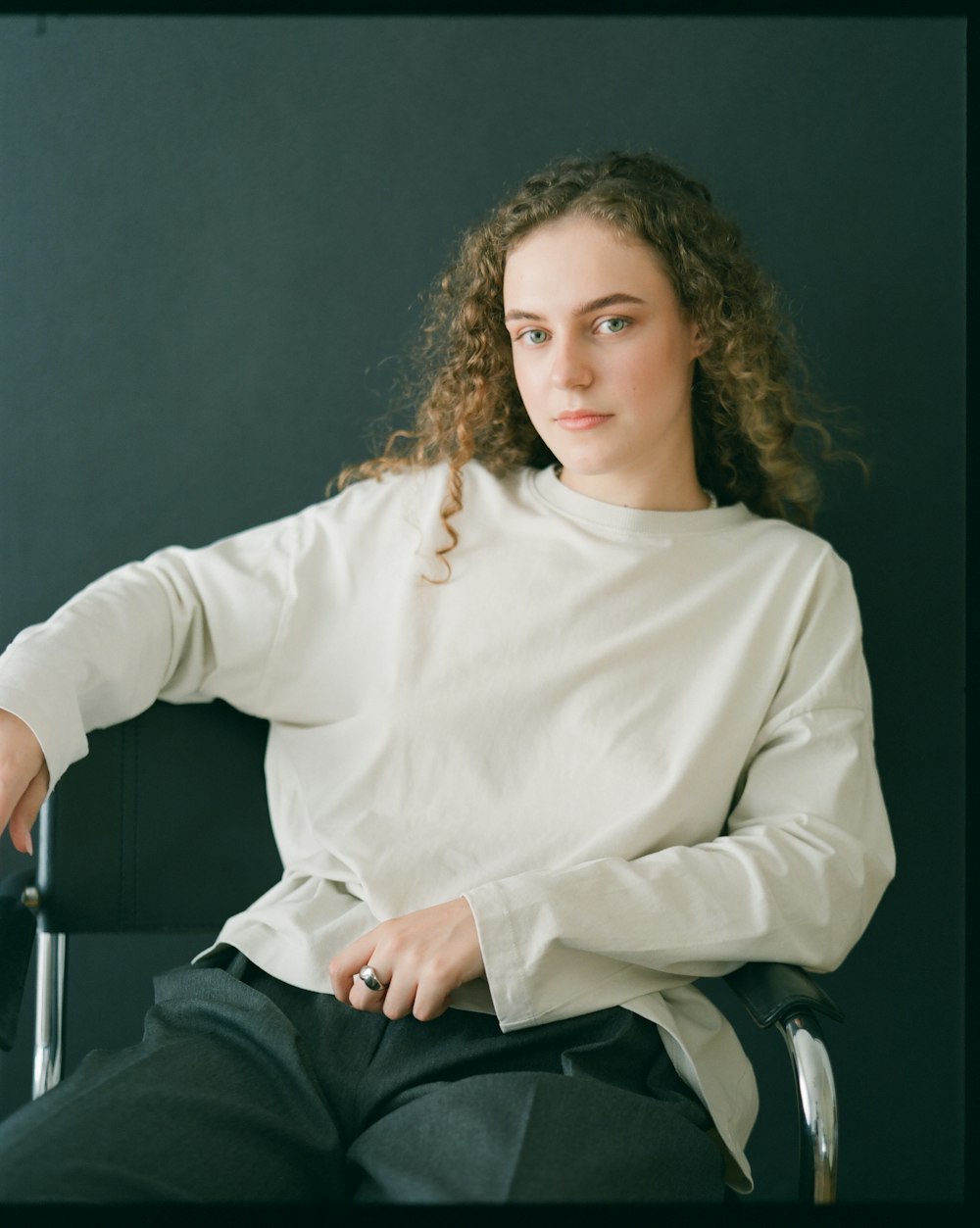 a woman sitting in a chair wearing a white shirt