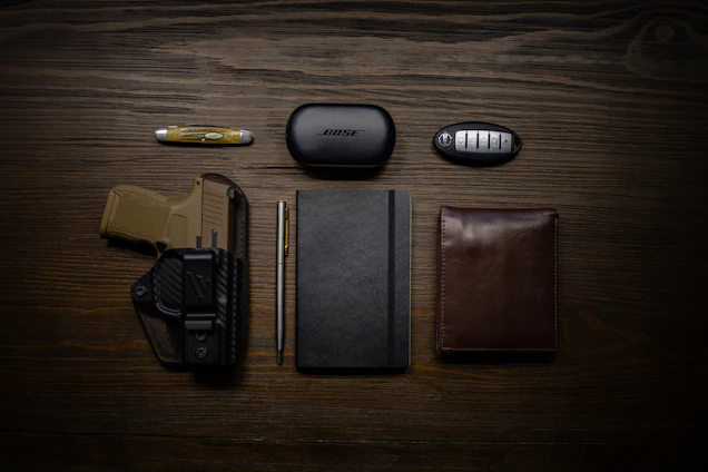 A minimalist flat lay of everyday carry items on an olive green and sand background.