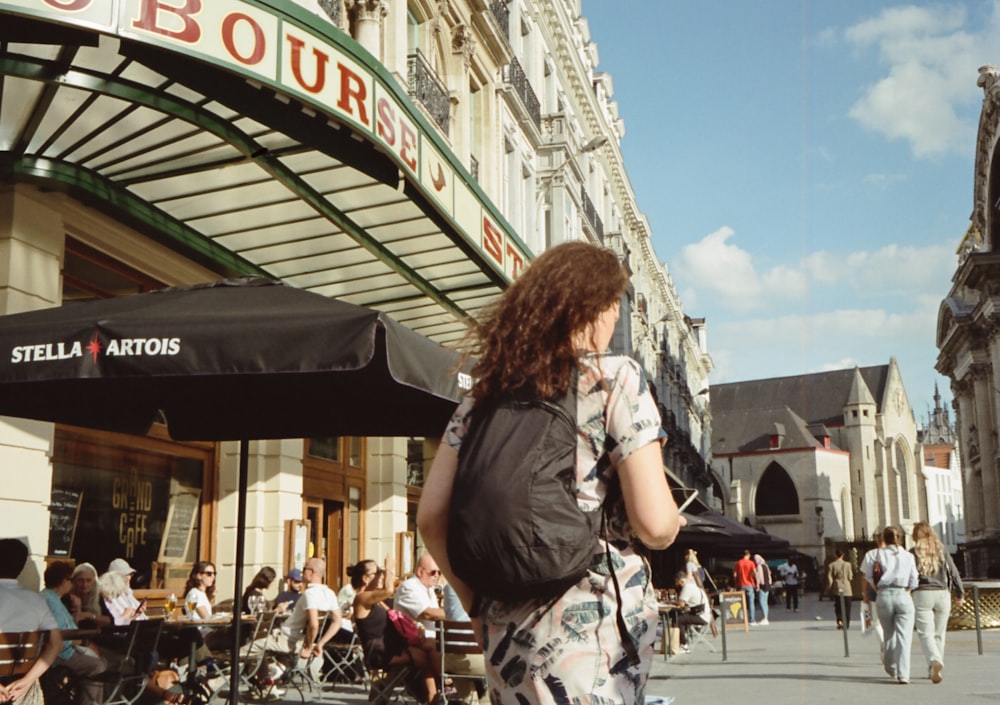 a woman walking down a street with a black umbrella