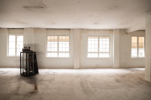 an empty room with three windows and a clock