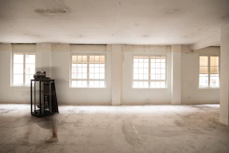 an empty room with three windows and a clock