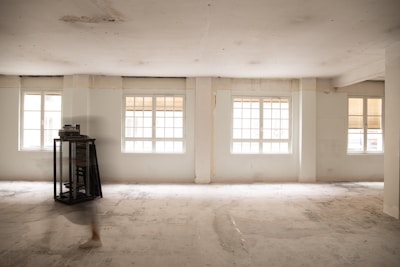 an empty room with three windows and a clock