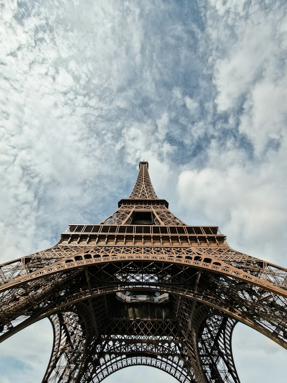 the top of the eiffel tower under a cloudy sky