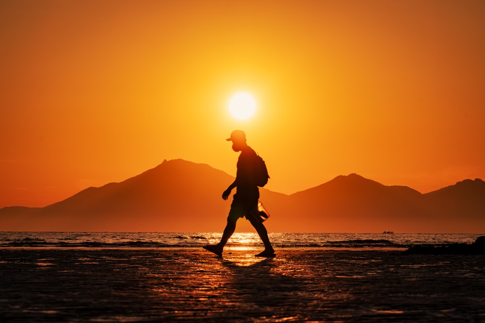 a person walking on a beach at sunset