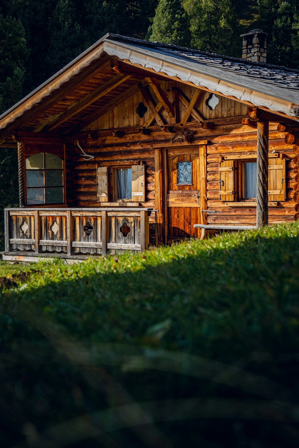 Uma cabana de madeira fica no meio de um campo gramado