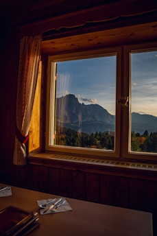 A cozy kitchen nook with a wooden table, freshly baked bread cooling by a sunny window framed with mountain views.