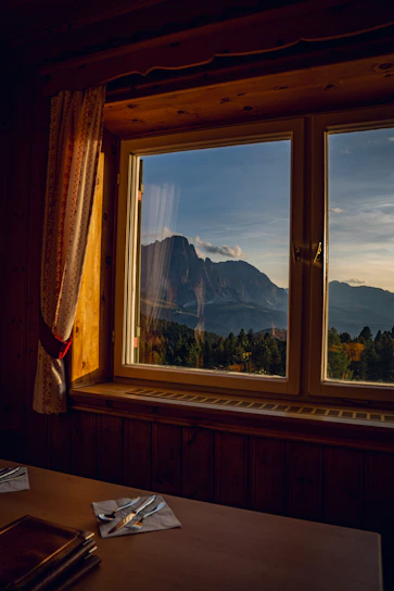 Cozy wooden room with panoramic mountain view at sunrise.