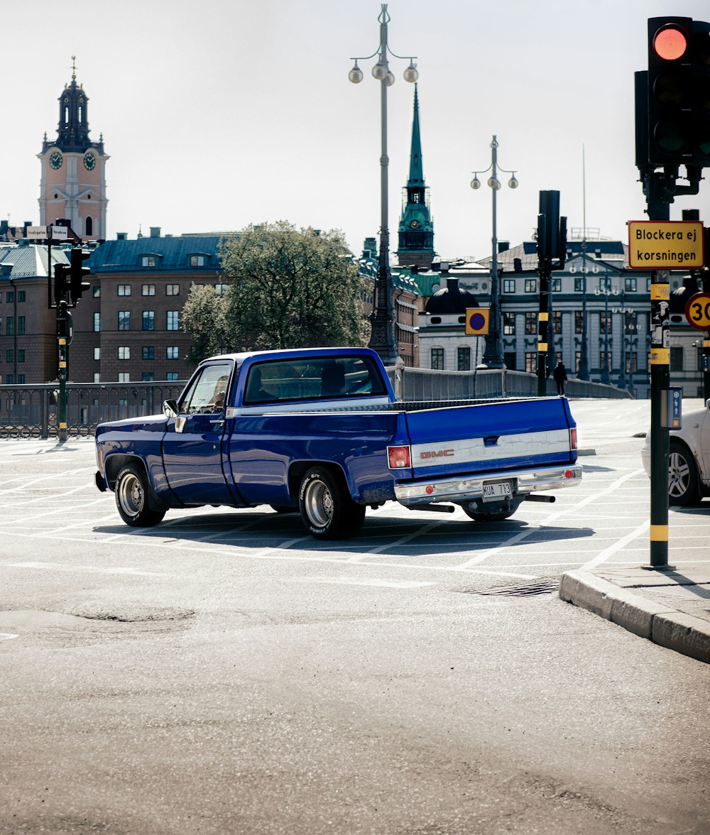 a blue pick up truck driving down a street