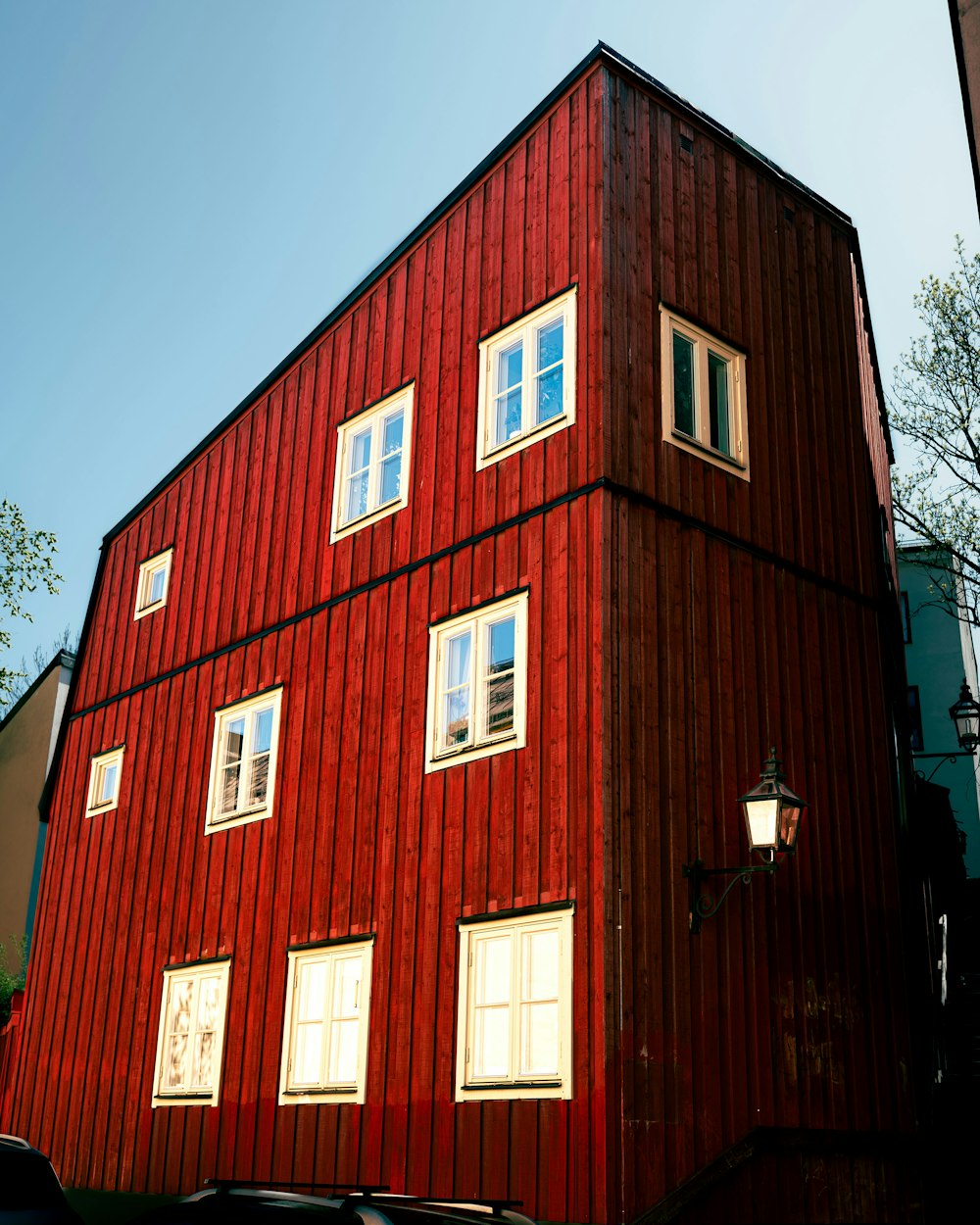 a tall red building with three windows on the side of it