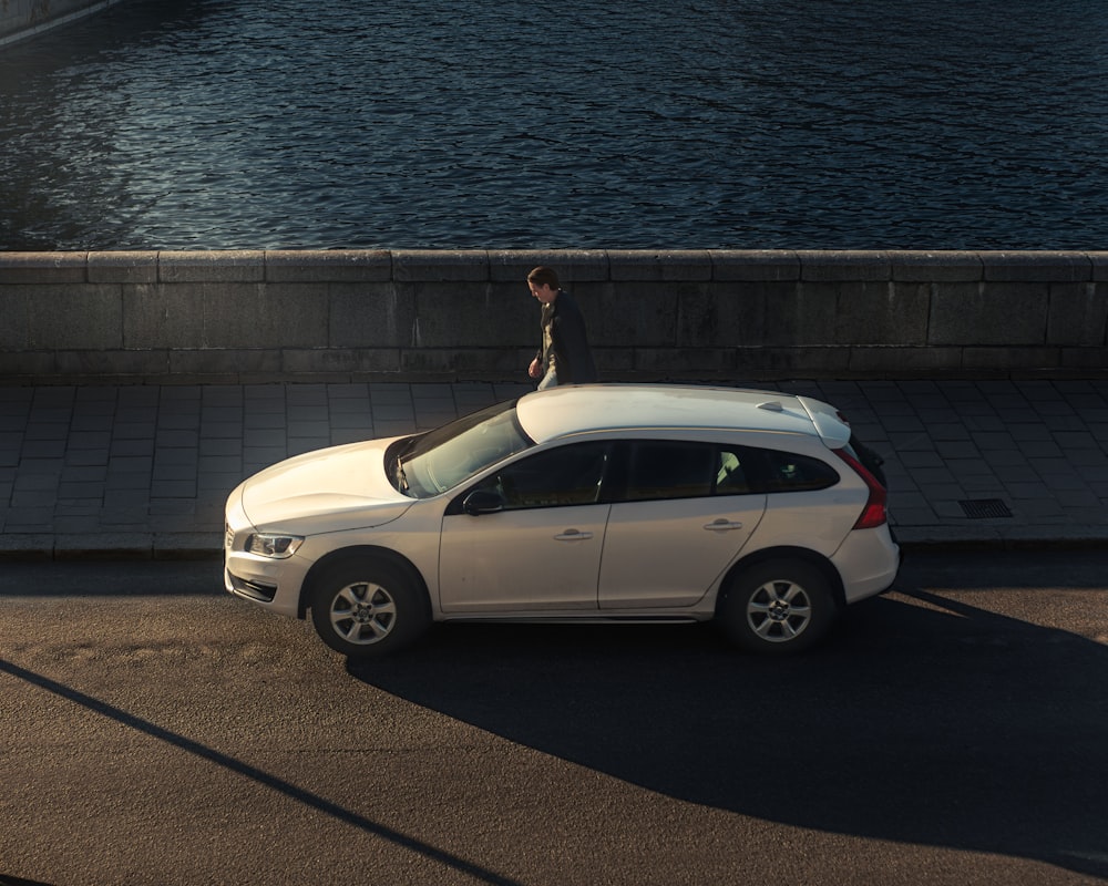 una persona in piedi sul tetto di un'auto bianca