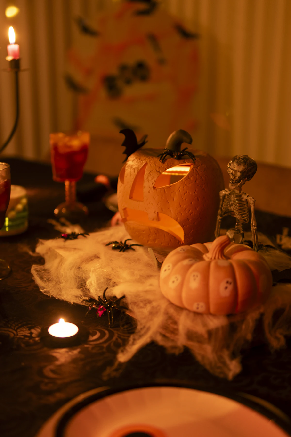 A table of Halloween decorations and lit candles in a dark room