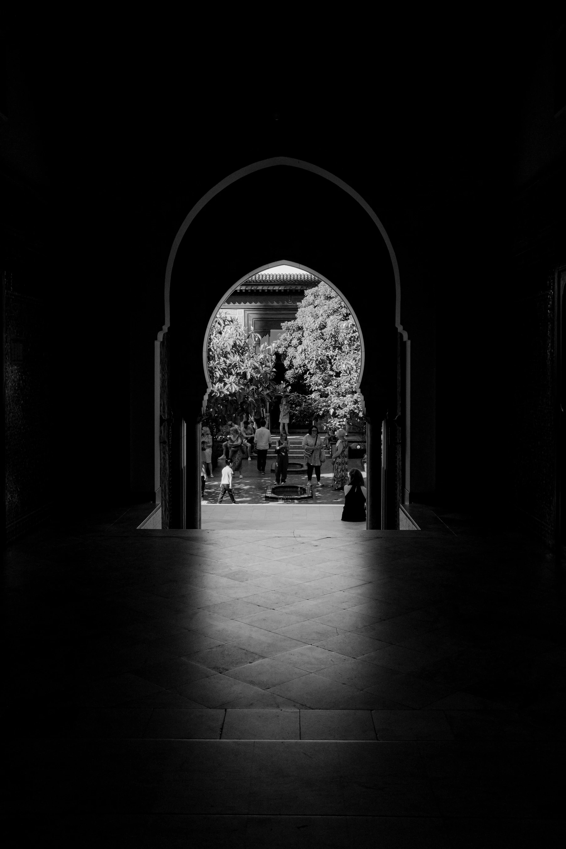 A Solitary Person Walking Through A Dark Arched Tunnel