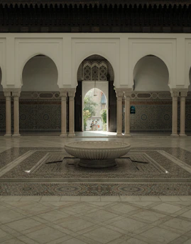 A sunlit Moroccan riad courtyard with lush greenery and intricate tilework.