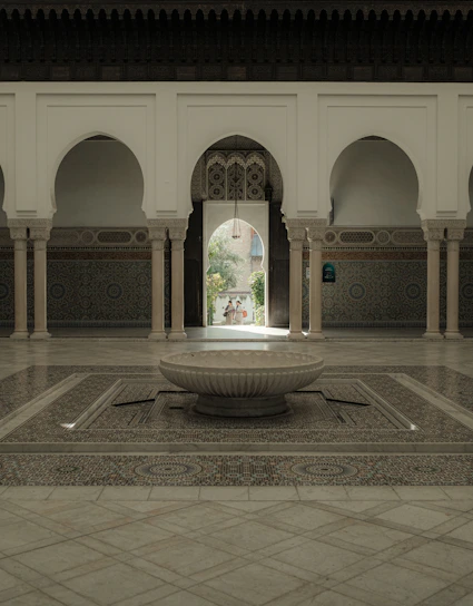 Sunlit courtyard of a Marrakech riad with intricate tilework and lush greenery.