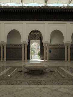 A cozy Moroccan riad courtyard bathed in warm golden light with intricate mosaic tiles and lush greenery.