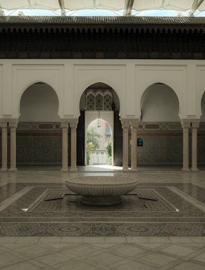 A cozy Moroccan courtyard with vibrant tiles and a small fountain, inviting visitors to reach out.
