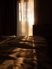 the sun is shining through the curtains on a bed