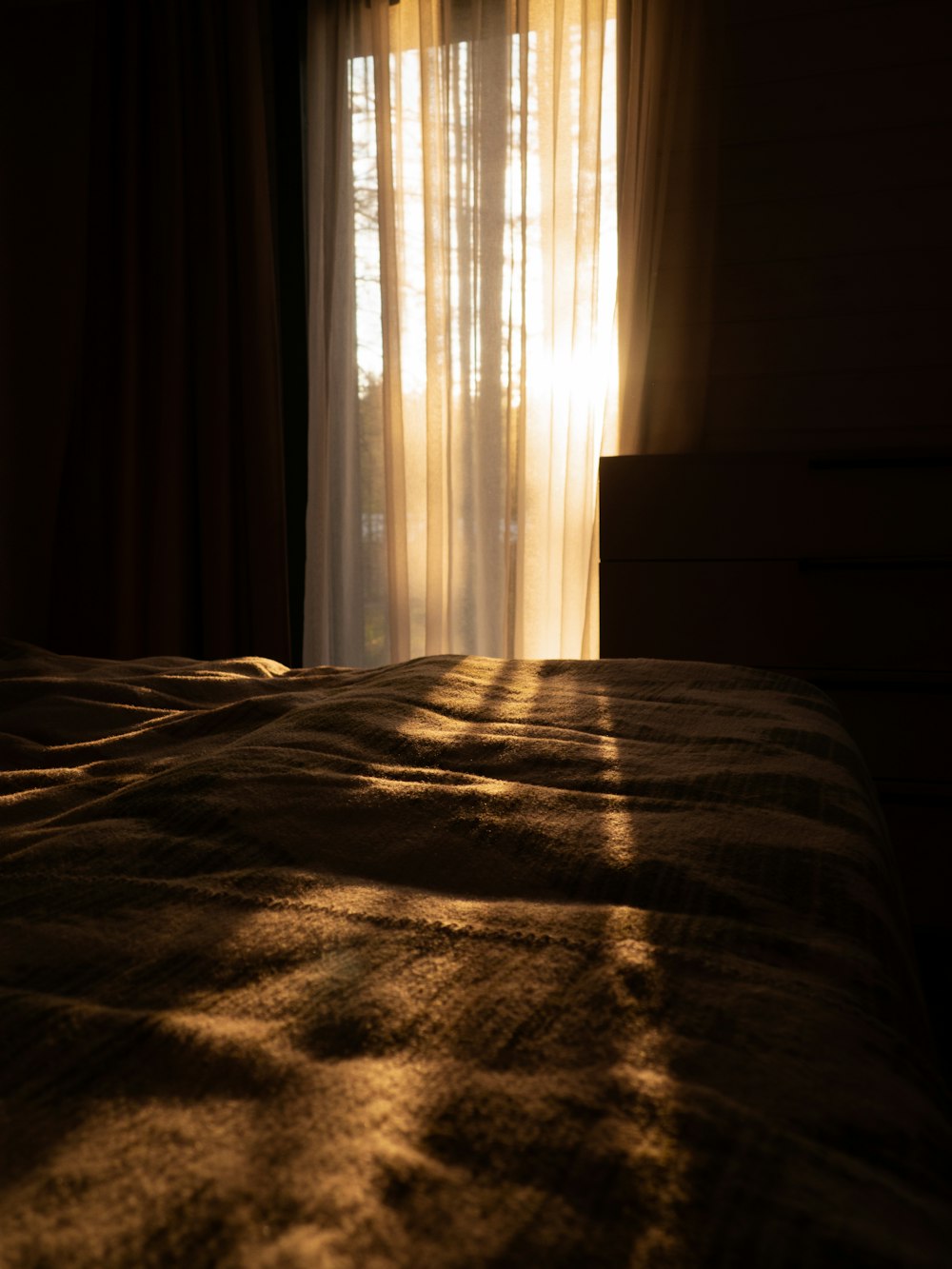 the sun is shining through the curtains on a bed
