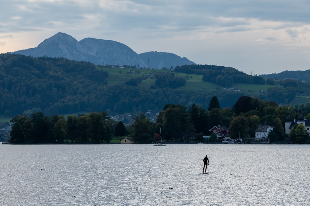 une personne debout sur une planche de surf au milieu d’un lac