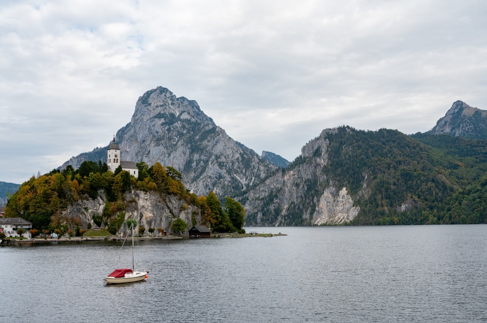 a boat floating on top of a lake next to a mountain