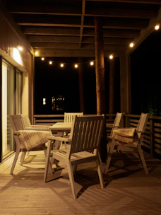 An inviting outdoor patio with comfortable seating, soft cushions, and warm string lights overhead at dusk.