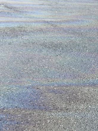 Close-up of freshly sealed asphalt with bright gold accents reflecting in sunlight