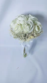 An elegant bridal bouquet featuring white and baby blue flowers resting on a black satin ribbon.