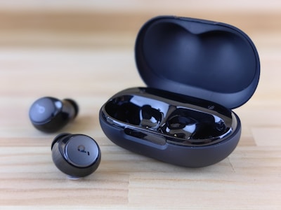 Modern wireless earbuds displayed in their charging case on a smooth black surface.