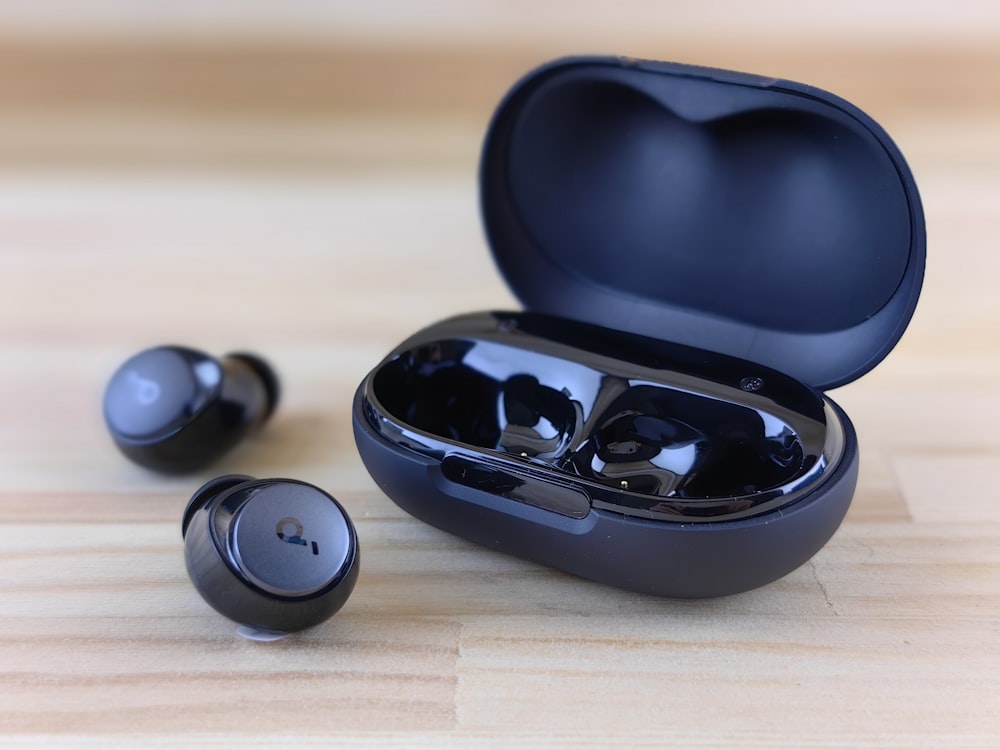a pair of black ear buds sitting on top of a wooden table