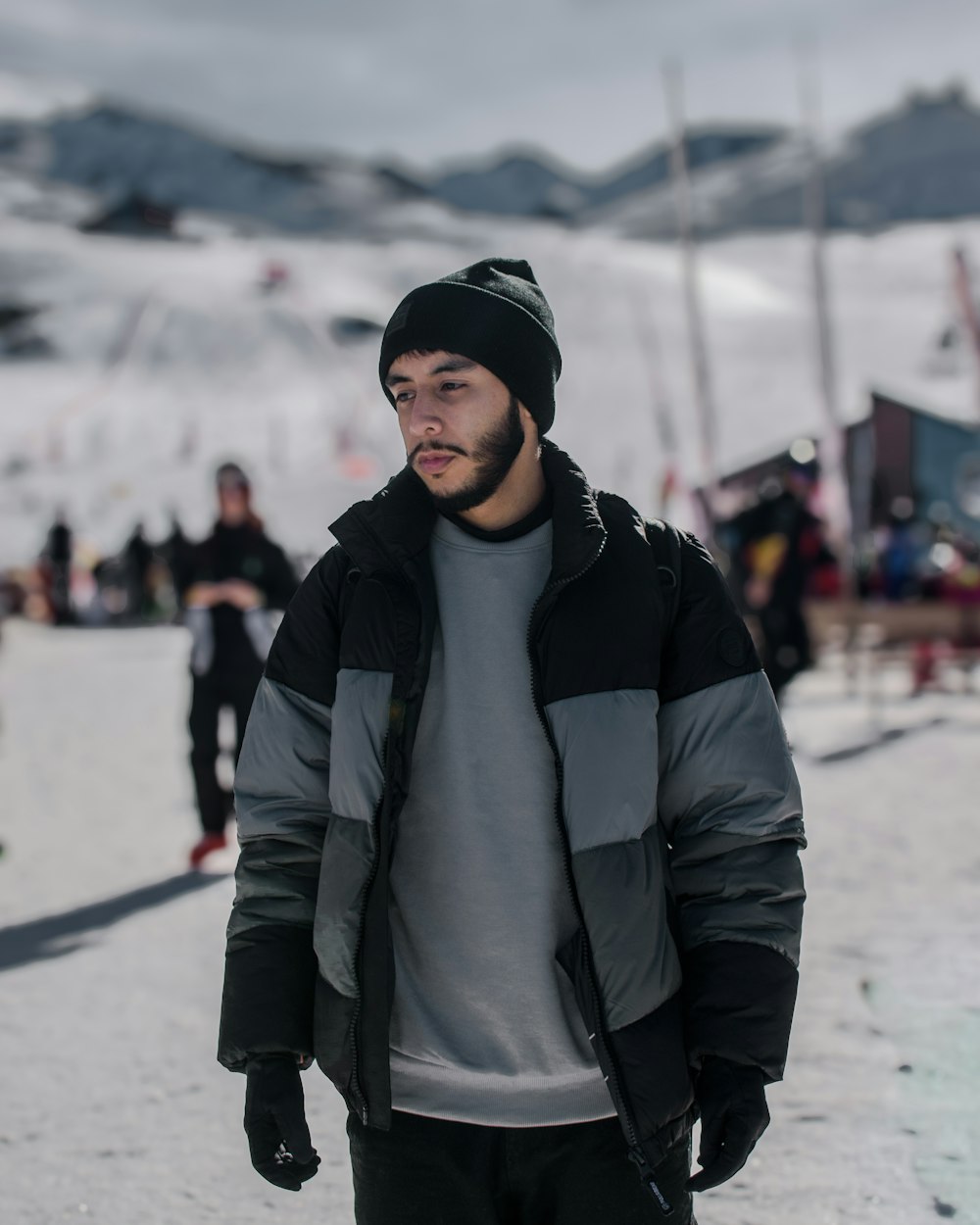 Ein Mann steht im Schnee und trägt eine schwarz-graue Jacke