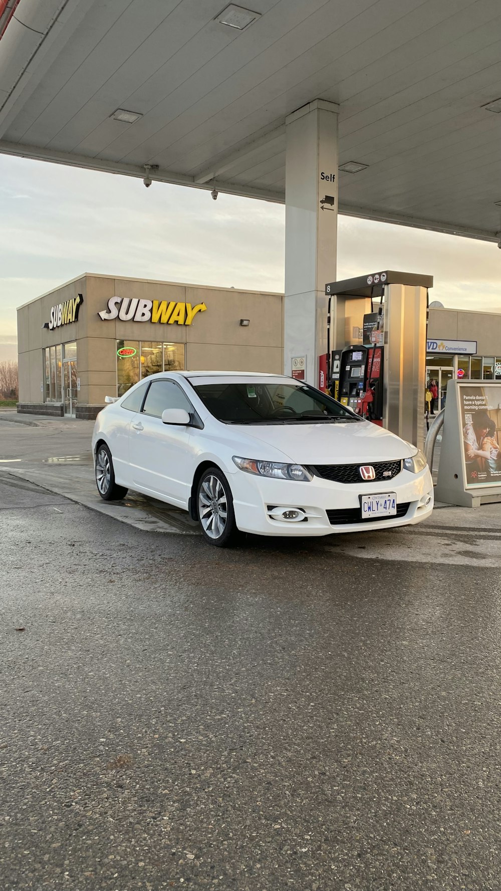 um carro branco estacionado em frente a um posto de gasolina