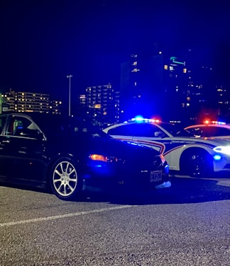 Tow truck assisting a car at night with city lights in the background