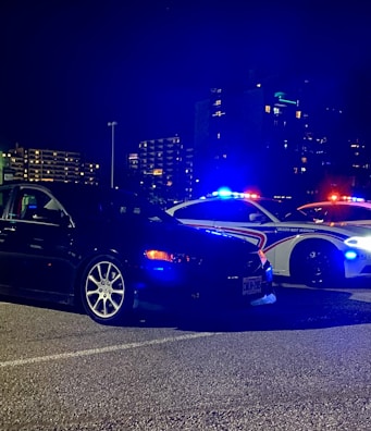 Nighttime scene of a car being boosted with portable lights illuminating the area