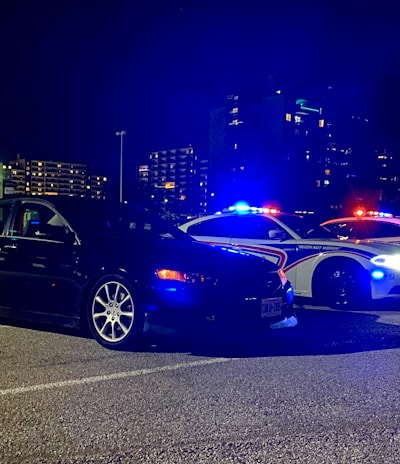 Night scene of a tow truck with flashing lights helping a stranded car.