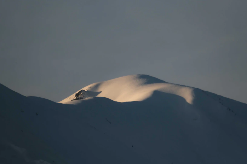 A serene snowy mountain peak bathed in soft morning light, evoking calm and exclusivity.